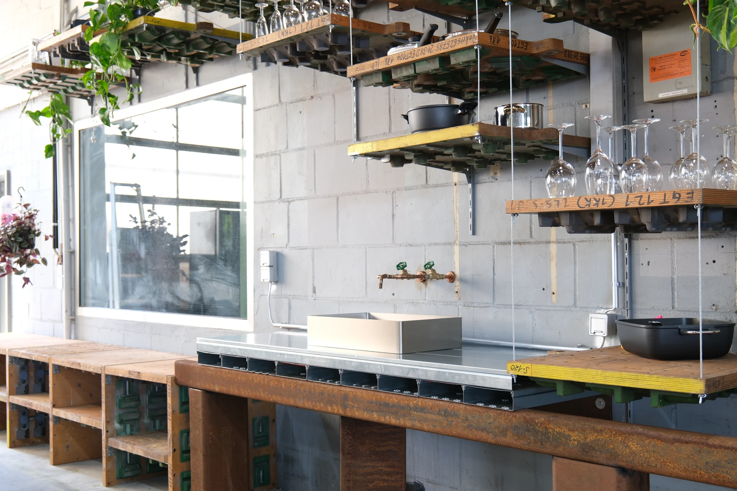 A kitchen at FELD.WERK with a stainless steel sink and worktop supported by reused timber units