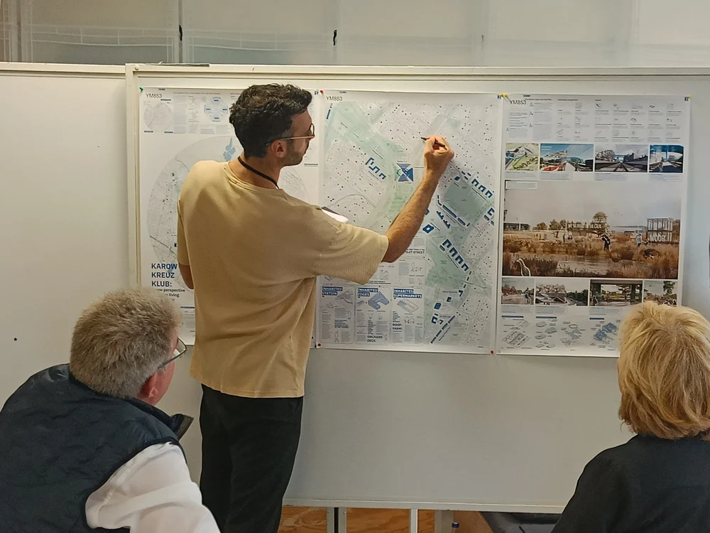 A participant marking up drawings on a workshop wall